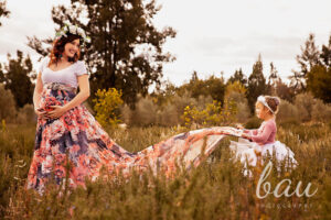 Outdoor family maternity photoshoot in Pretoria with a small child in a pink dress and white tutu holding her pregnant mother's floral gown
